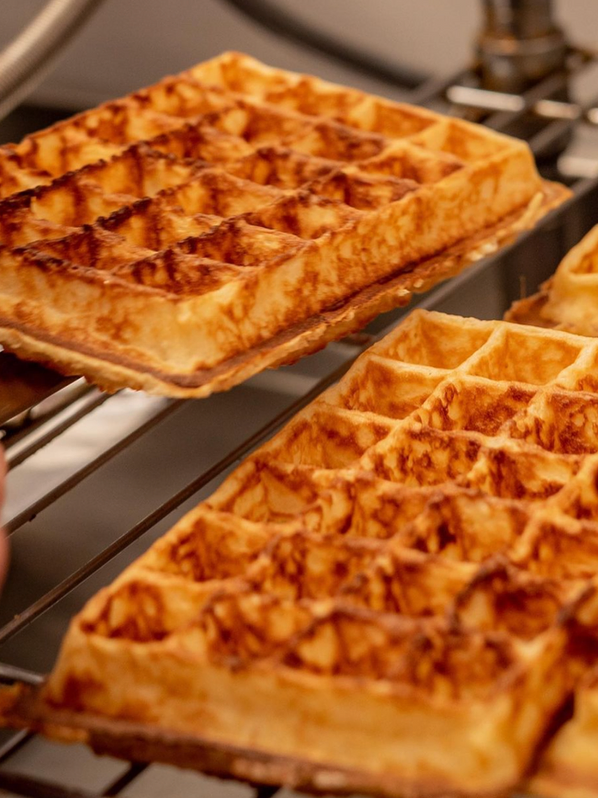 Gaufres maison dorées et croustillantes, servies avec des toppings gourmands comme du chocolat fondu et des fruits frais.